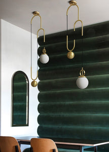 2 Madorne pendant lights hanging on a ceiling against a green backwall