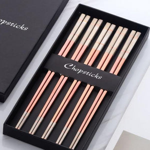 5 pairs of rose gold with white colored ends chopsticks in a black box