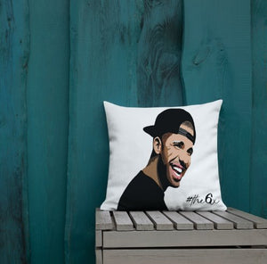 Throw pillow of Drake's face printed placed on a bench against a teal wooden wall