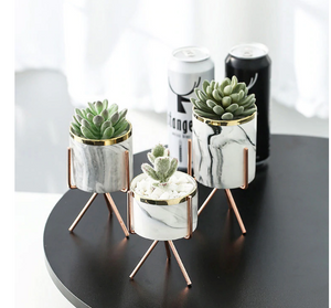 1 set of 3 marble glazed planter pots with gold iron stands in different sizes placed on a black table