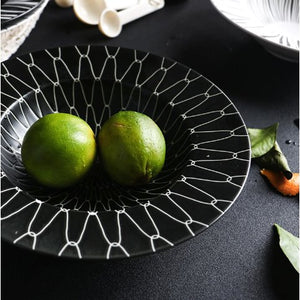 DEJAVU DINNERWARE BLACK WITH WHITE GEOMETRIC PATTERN PRINTED AND 2 GREEN FRUITS PLACED IN THE CENTER 