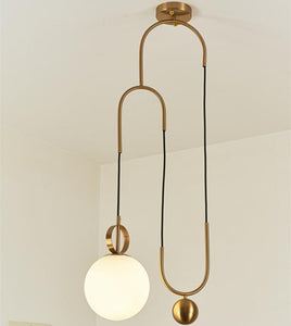 Madorne pendant light with gold plated ball mounted on a ceiling