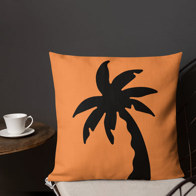 orange colour cushion cover with a black palm tree print placed on a chair