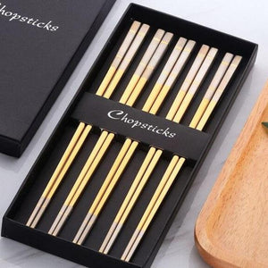 5 pairs of yellowish gold with white colored ends chopsticks in a black box