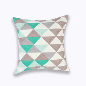 mix of teal, grey, brown and white in geometric patterns printed on a cushion cover