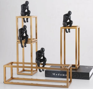 4 decorative figurines of a man statue sitting on a gold rectangular tower
