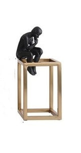 decorative figurine of a man statue sitting on a gold rectangular tower