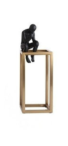 decorative figurine of a man statue sitting on a gold rectangular tower