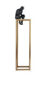 decorative figurine of a man statue sitting on a gold rectangular tower
