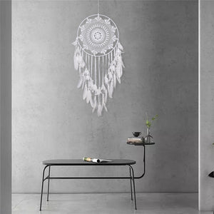 white dreamcatcher hanging on a grey wall over a table