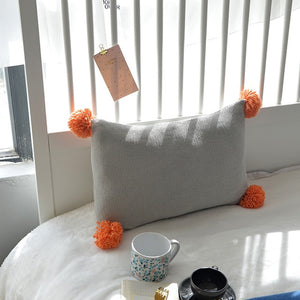 grey cushion with orange tassels on all four ends FunkChez