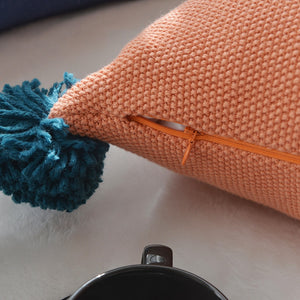 closeup of a concealed zip on an orange cushion with a blue tassel 