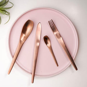 ombre cutlery set of a knife, fork and 2 spoons placed on a pink plate