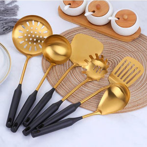 6 black and gold utensils set on a placemat near cups of tea, sugar and milk