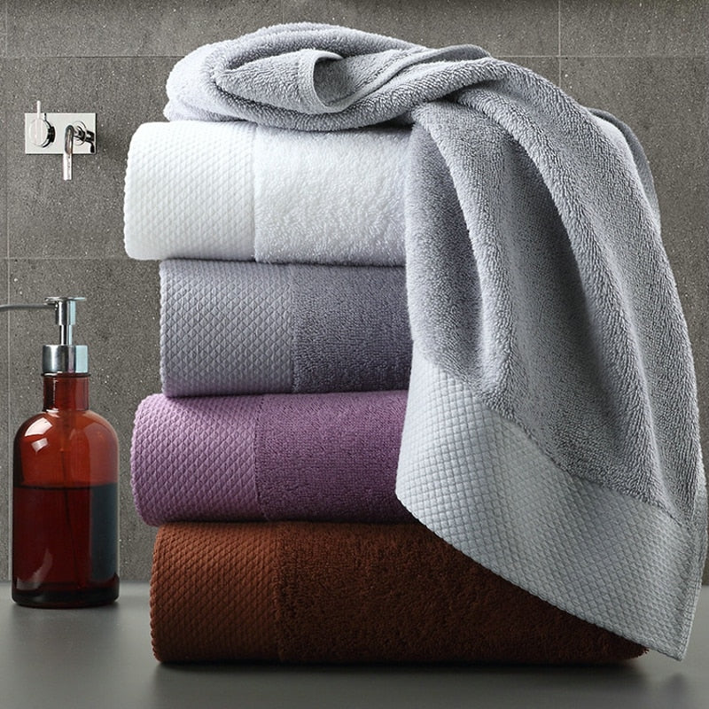 set of 4 luxury towels stacked near a hand wash on a vanity counter