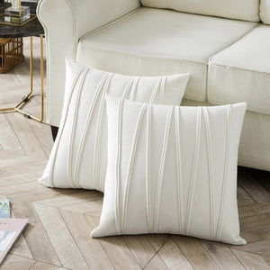 2 cushions in ivory white from the Nordane cushion collection placed besides a couch