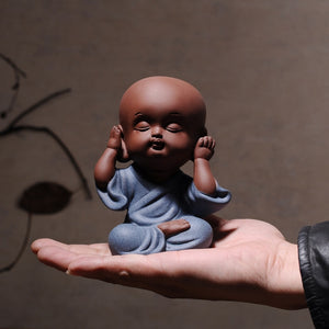 hand holding a baby figurine expressing hear no evil