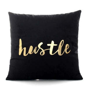 The word Hustle printed in gold on a black polyester throw pillow 