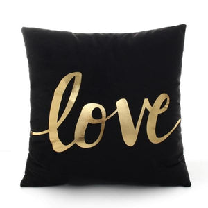 The word love printed in gold on a black polyester throw pillow 